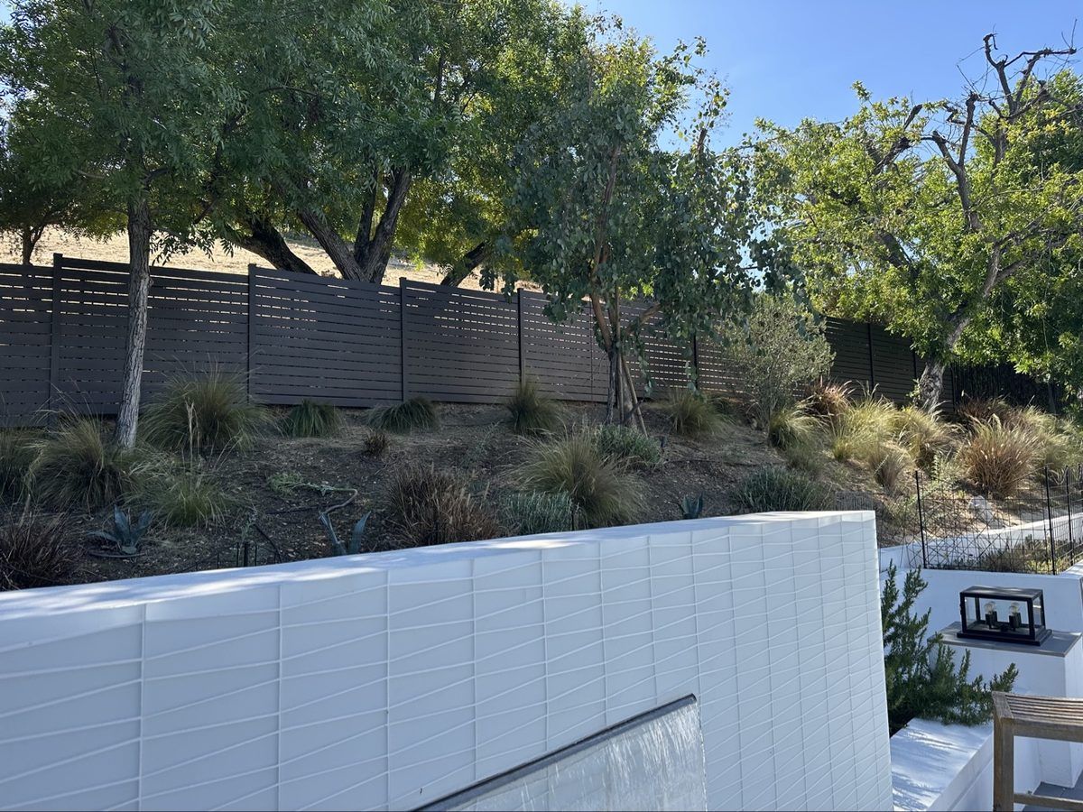 Modern horizontal-slat aluminum fence on a landscaped hillside in Los Angeles
