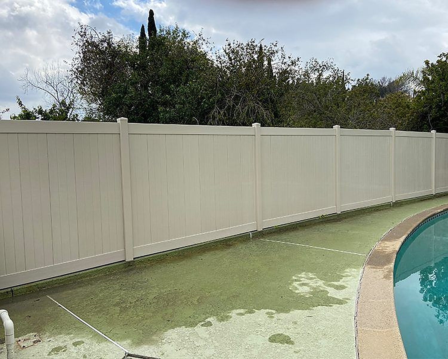 Tan vinyl privacy fence around a pool