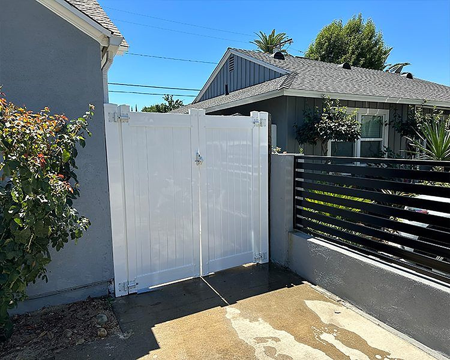 White vinyl gate beside a black aluminum slat fence