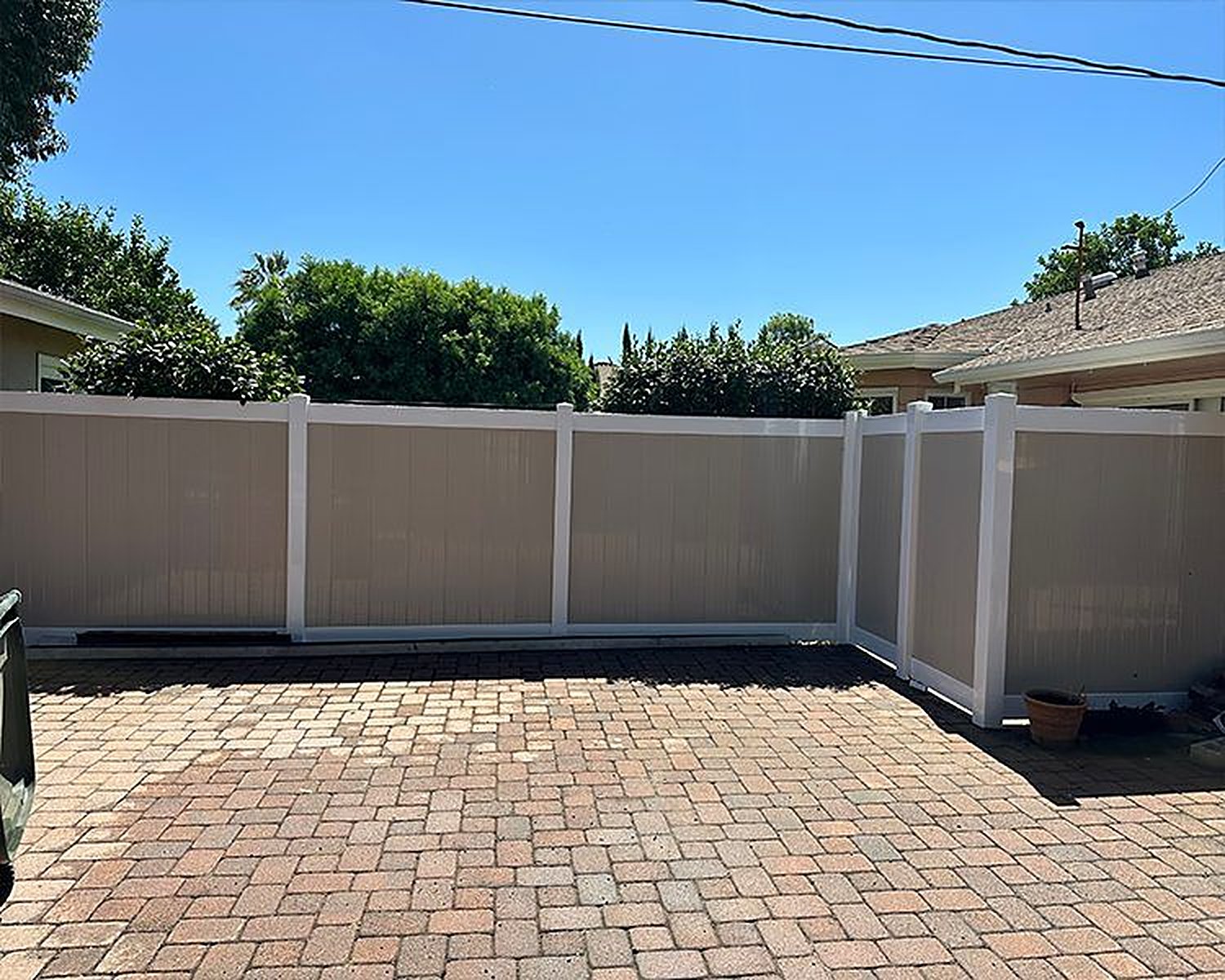 Tan vinyl privacy fence around a brick patio