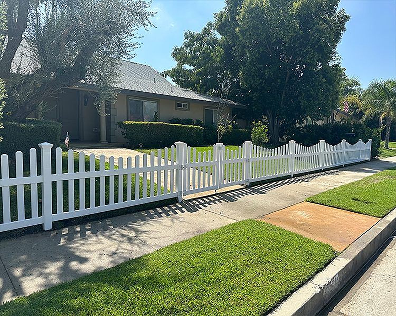 White vinyl picket fence along a sidewalk