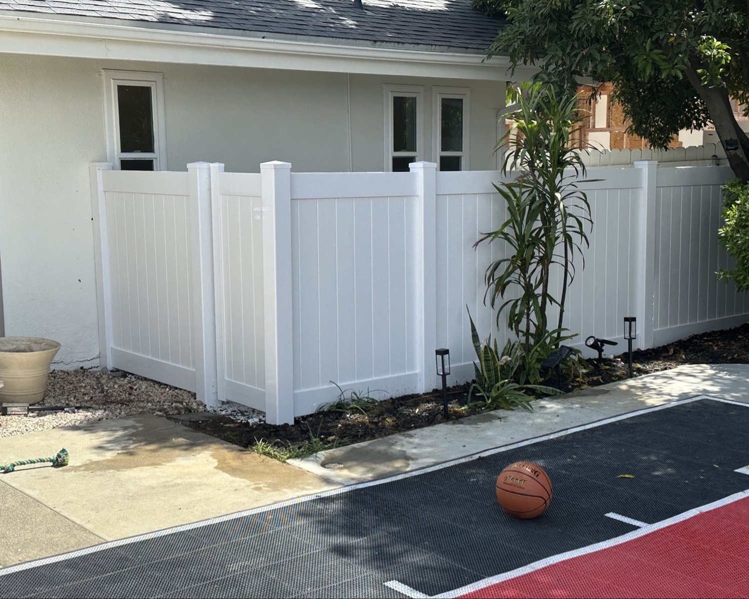 White vinyl privacy fence next to a basketball court
