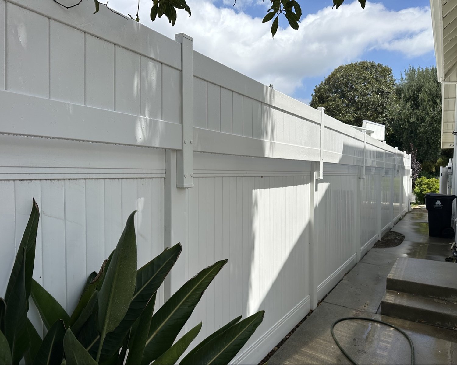 Close view of white vinyl privacy fence along a house