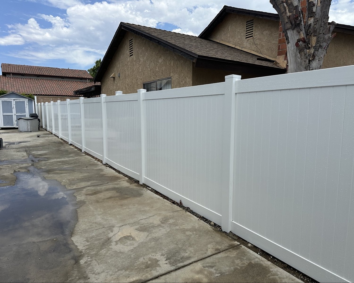 Long white vinyl privacy fence run beside a driveway
