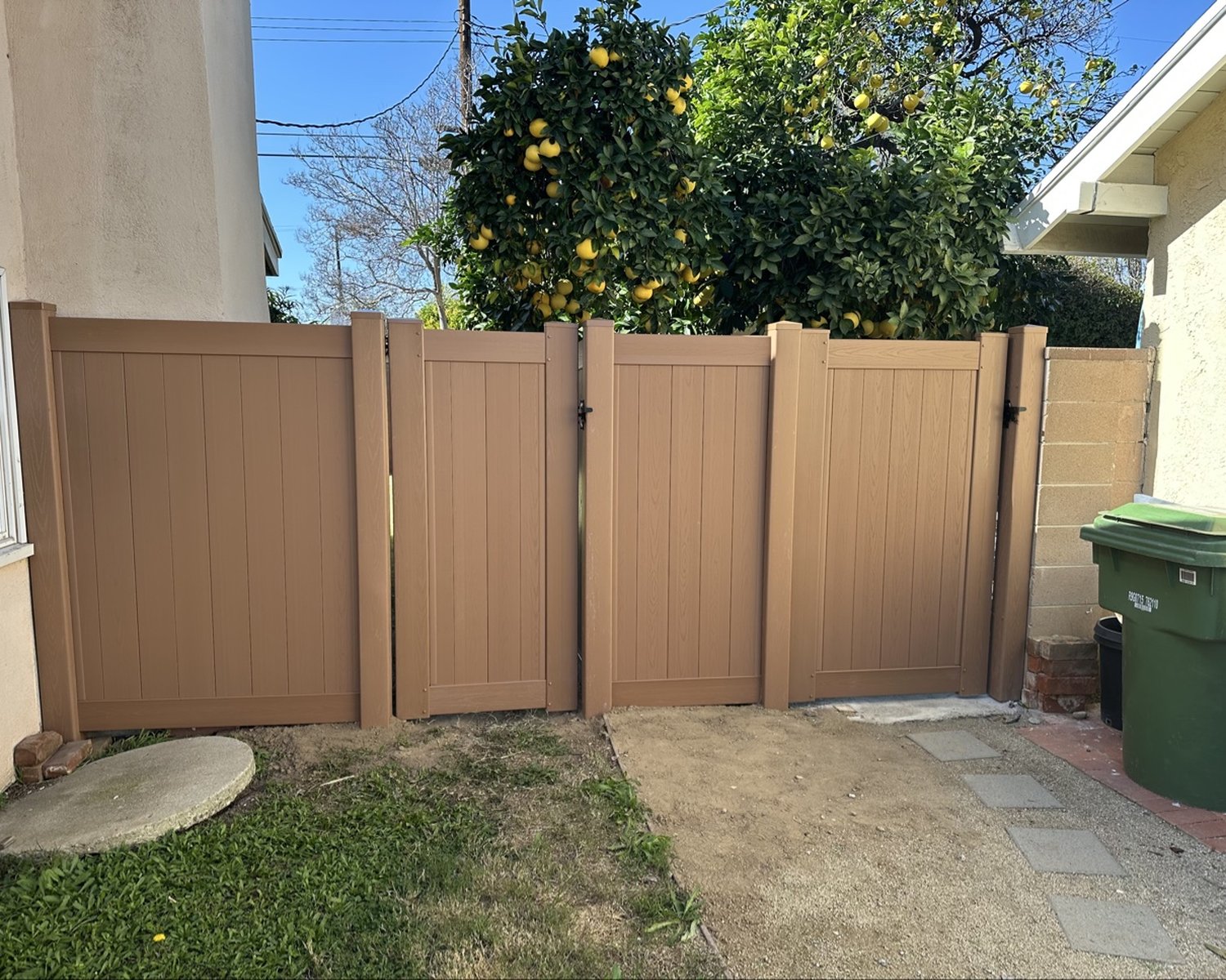 Close view of wood-look vinyl privacy fence by a walkway