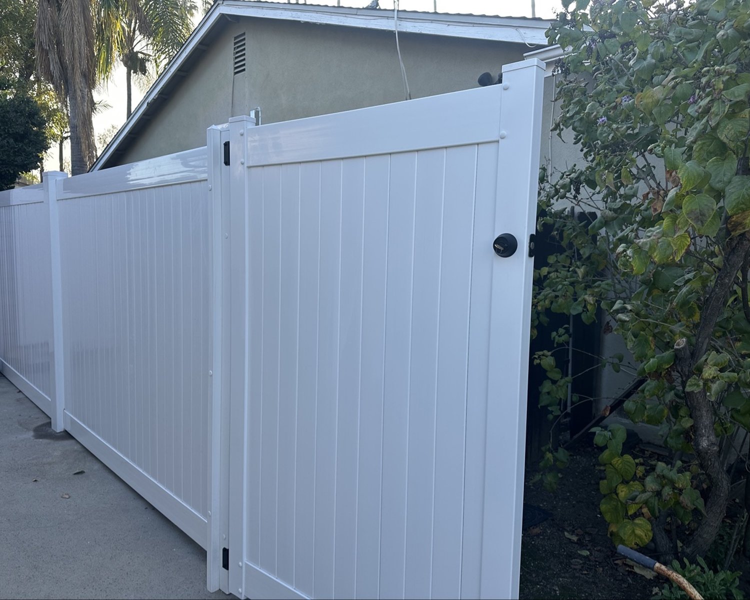 White vinyl fence with matching pedestrian gate on a driveway