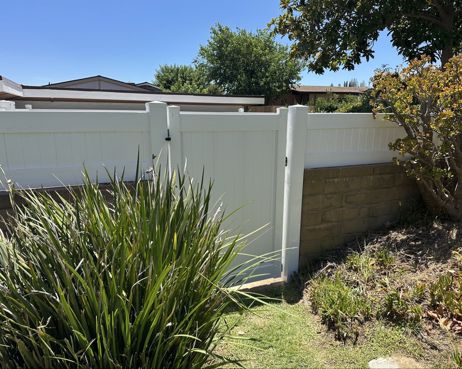 White vinyl pedestrian gate in a block wall with landscaping