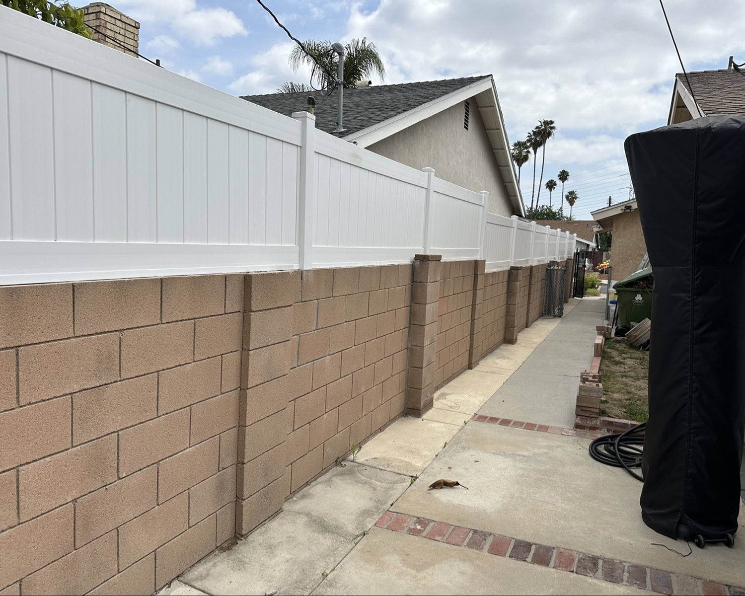 White vinyl privacy fence installed on top of a tan block wall