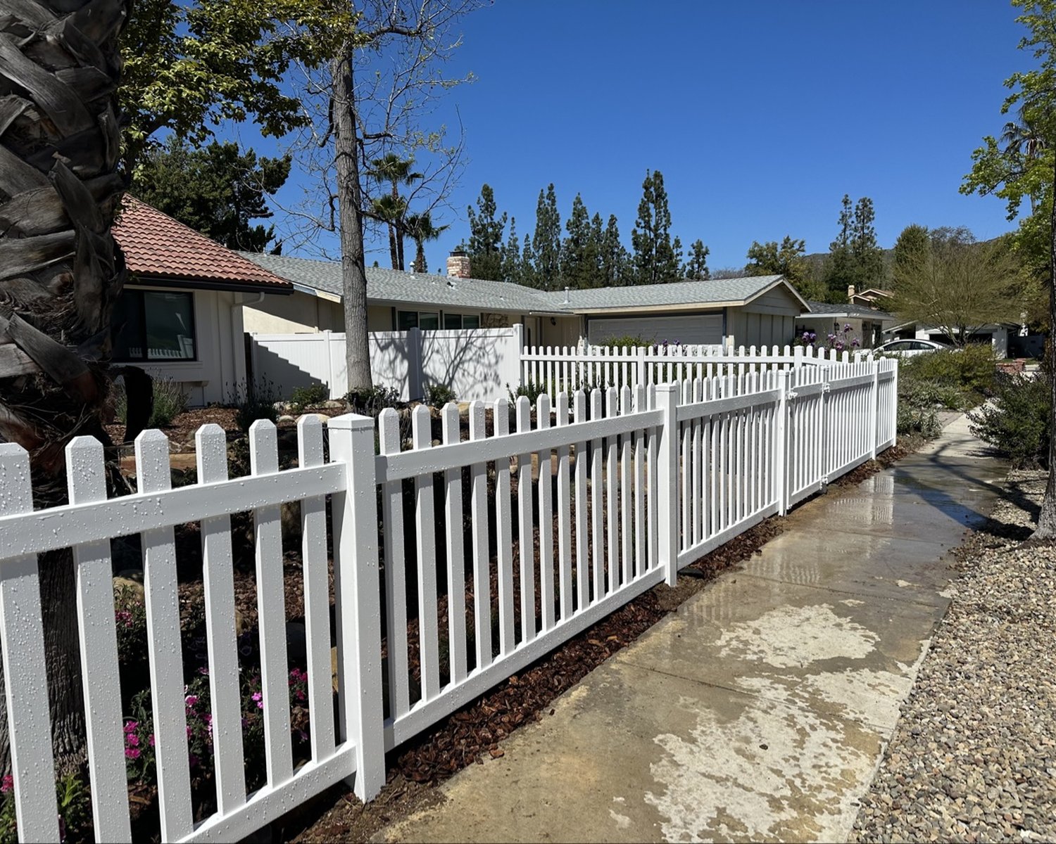White vinyl picket fence along a front-yard sidewalk