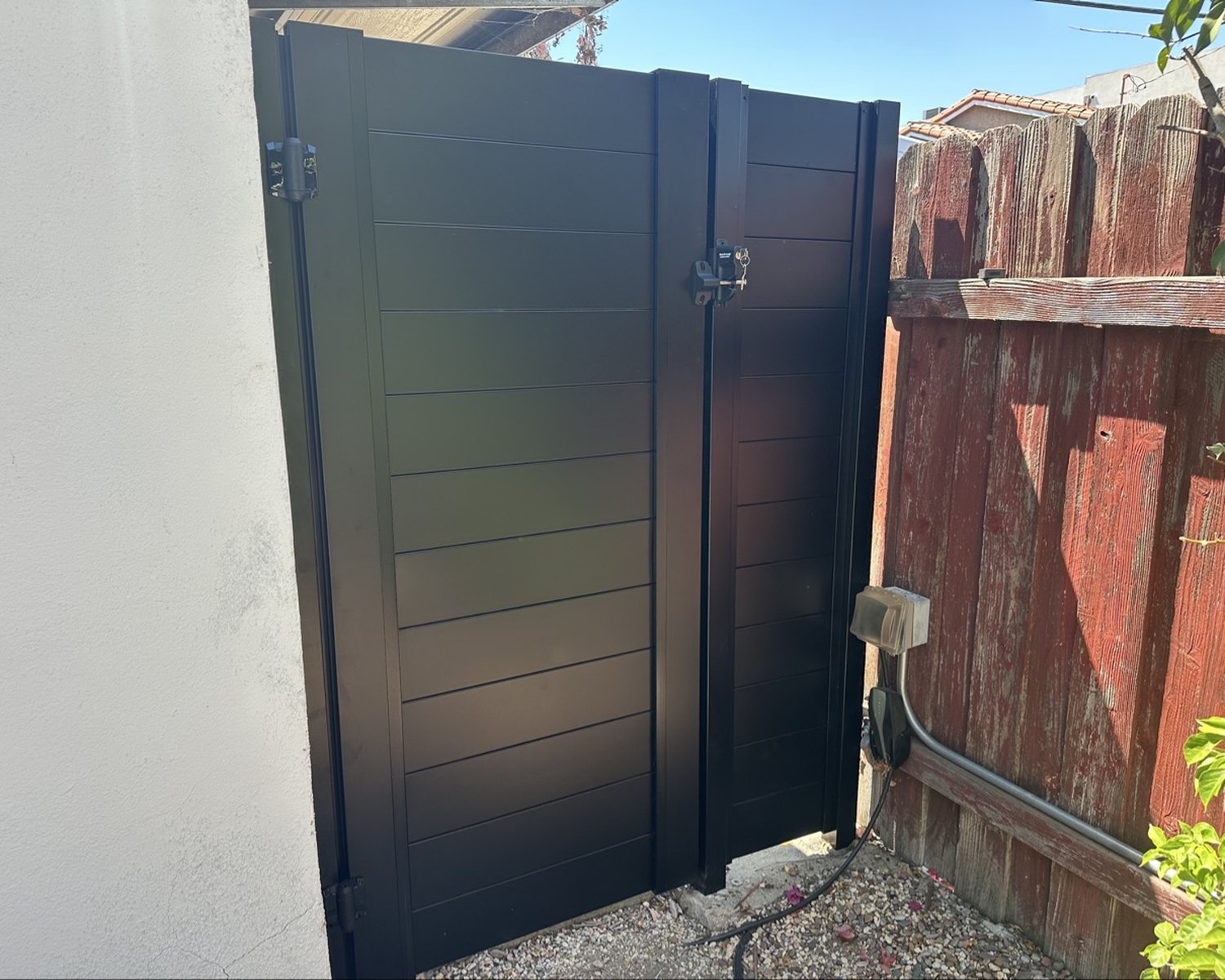 Black horizontal-slat pedestrian gate with latch and lock