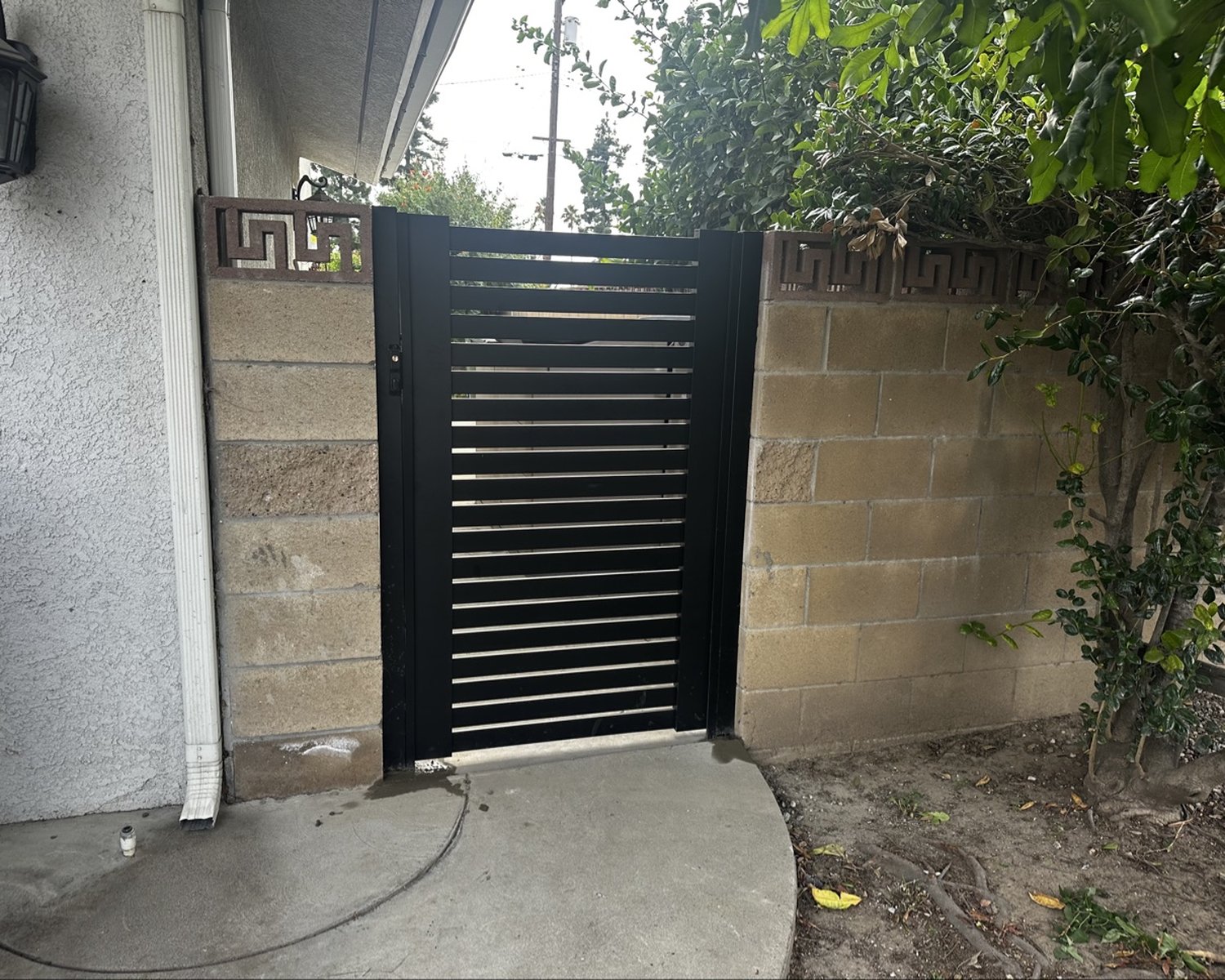 Black horizontal-slat pedestrian gate between block pillars