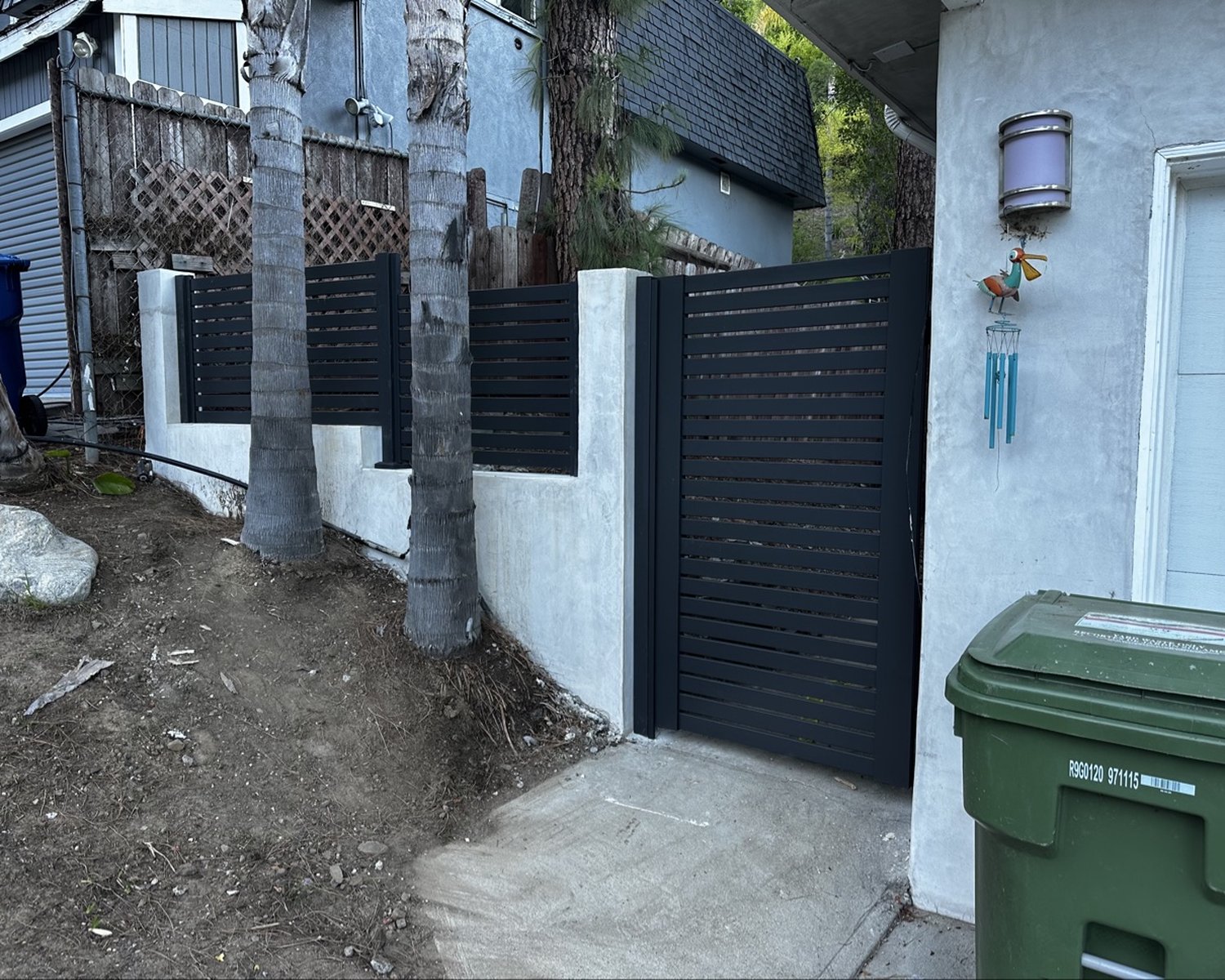 Black horizontal-slat gate and fence panels between white pillars