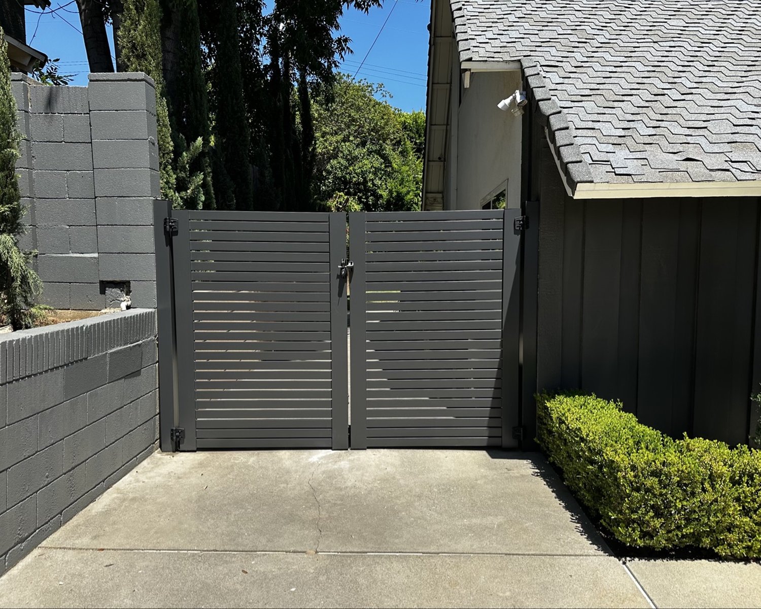 Dark gray horizontal-slat double gate between block walls