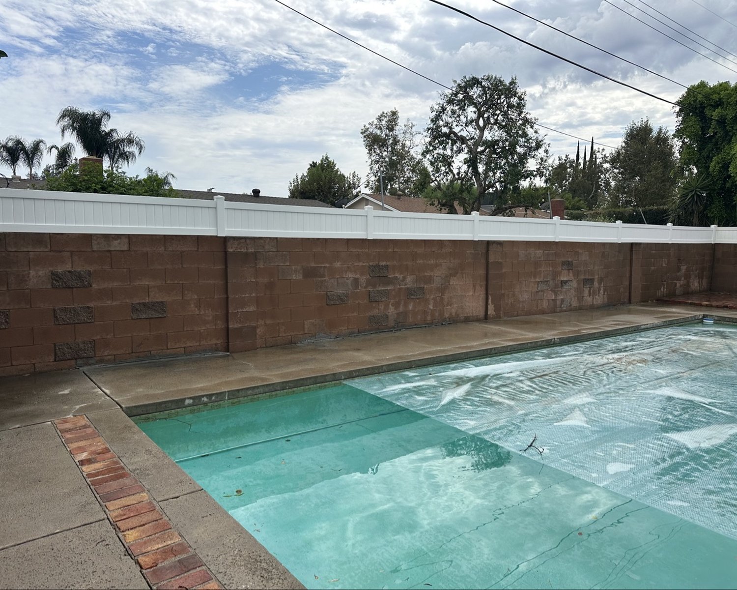 White vinyl wall topper on a block wall around a pool