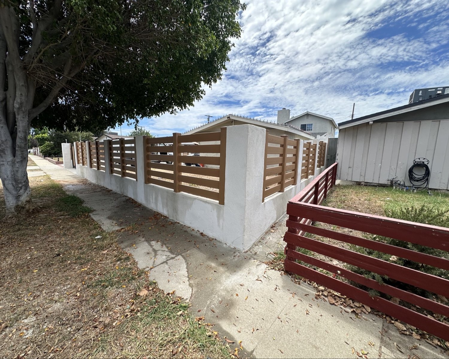 Wood-look horizontal-slat fence between stucco pillars