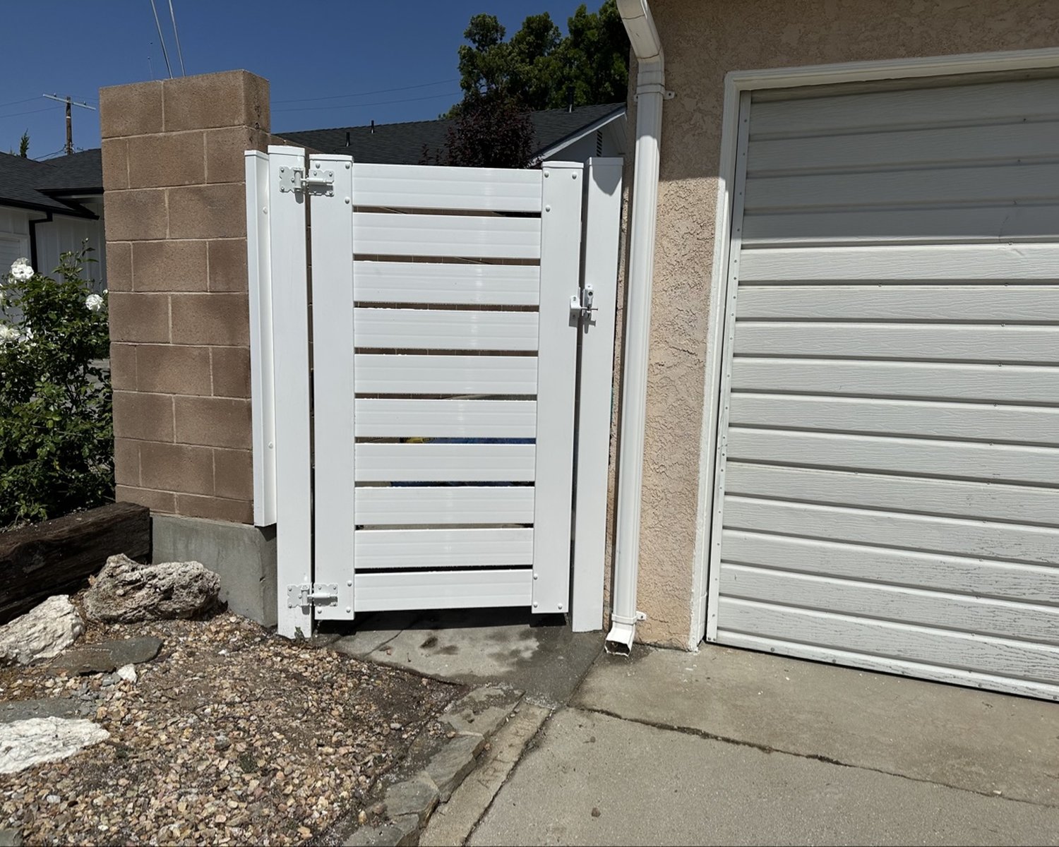 White horizontal-slat vinyl gate by a garage