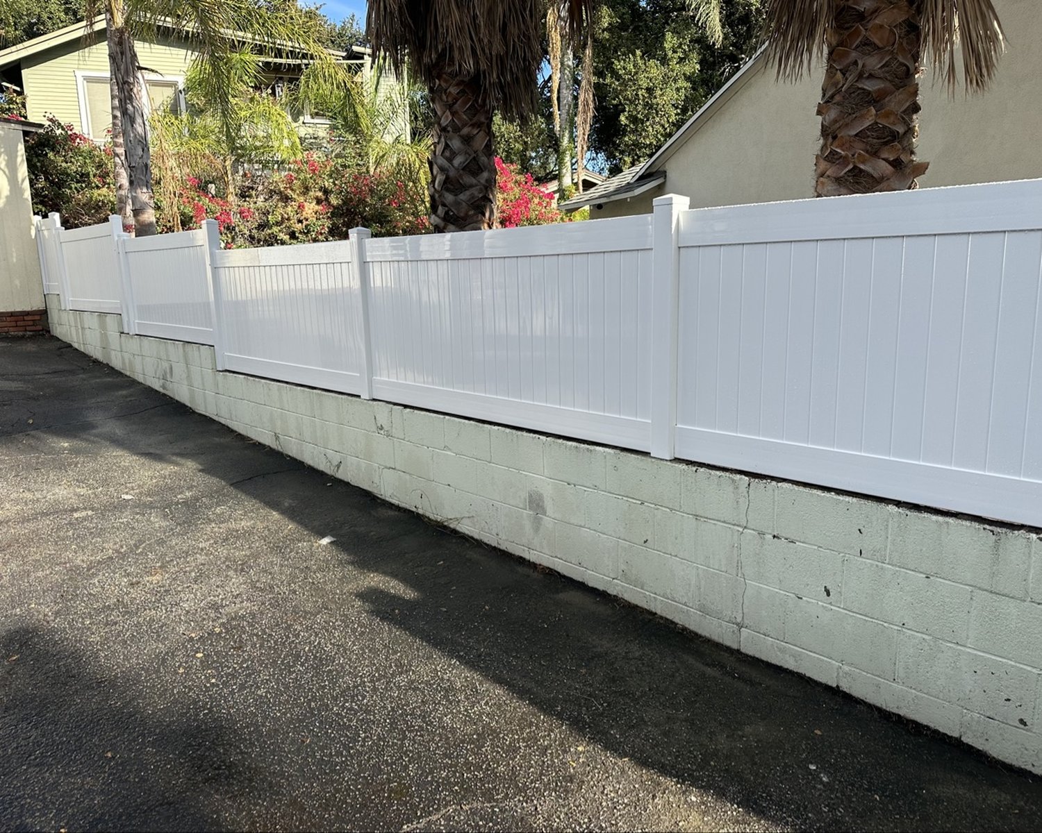 White vinyl privacy fence on a block wall by a driveway